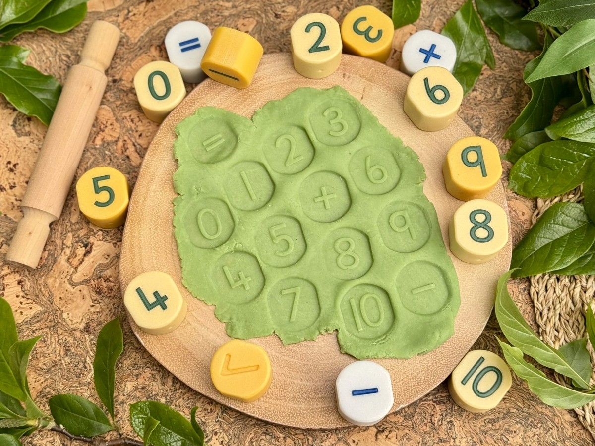 number stamping stones on a board with numbers stamped in green playdough